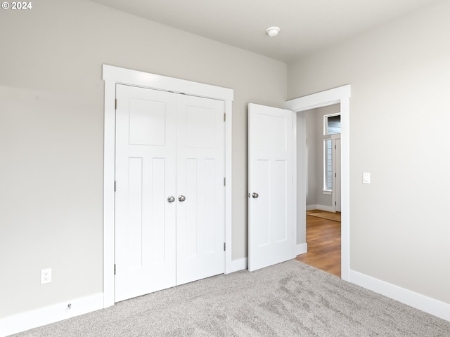 unfurnished bedroom with light colored carpet and a closet