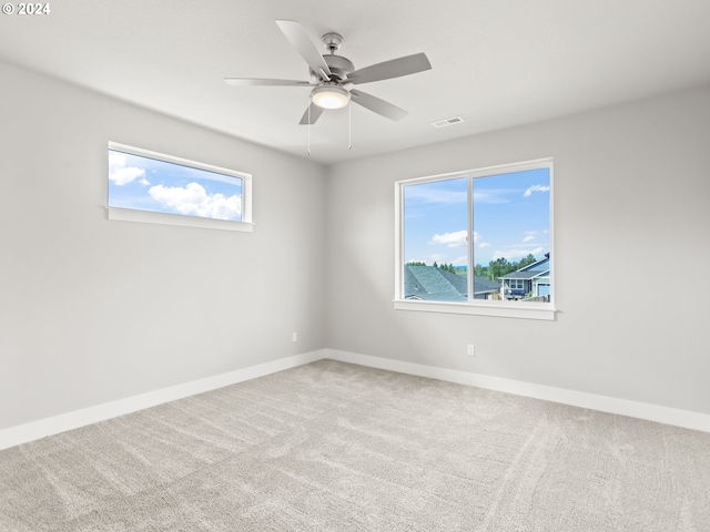 unfurnished room with a healthy amount of sunlight, ceiling fan, and carpet