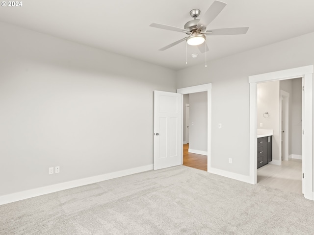 unfurnished bedroom with ensuite bathroom, ceiling fan, and light colored carpet