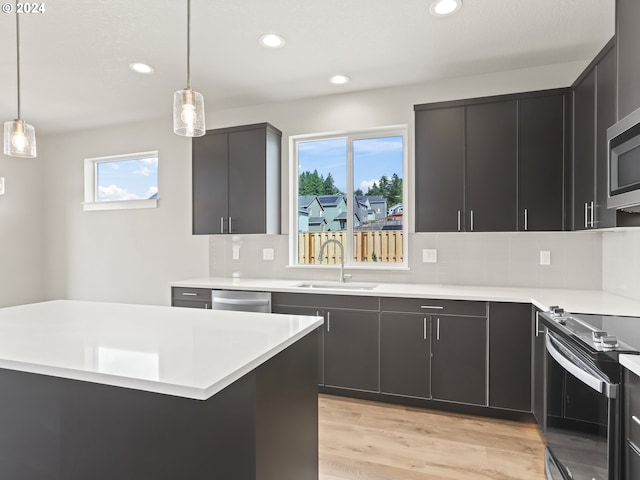 kitchen featuring decorative light fixtures, light wood-type flooring, decorative backsplash, and a healthy amount of sunlight