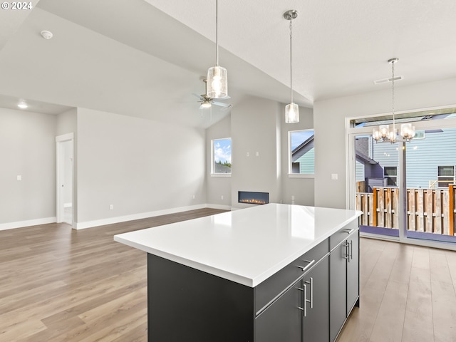 kitchen featuring decorative light fixtures, light hardwood / wood-style flooring, vaulted ceiling, and a center island