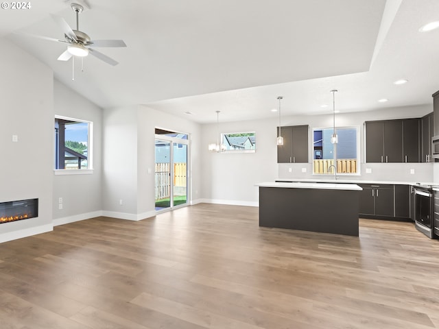 kitchen featuring hanging light fixtures, a kitchen island, light hardwood / wood-style flooring, appliances with stainless steel finishes, and ceiling fan with notable chandelier