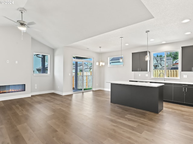 kitchen featuring ceiling fan with notable chandelier, a kitchen island, plenty of natural light, and hardwood / wood-style flooring