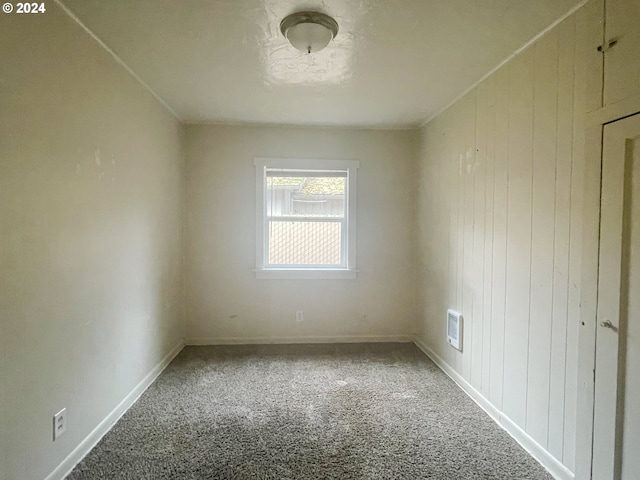 carpeted spare room with wood walls