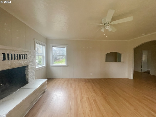 unfurnished living room featuring light hardwood / wood-style floors, a stone fireplace, and ceiling fan