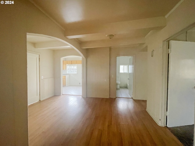 spare room featuring beam ceiling, crown molding, and light hardwood / wood-style flooring