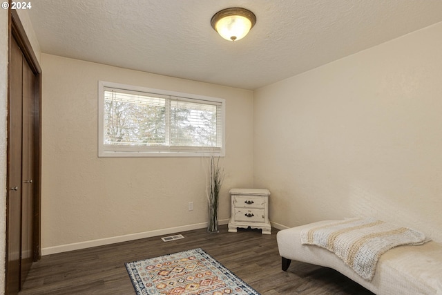 bedroom featuring a closet, dark wood-type flooring, and a textured ceiling