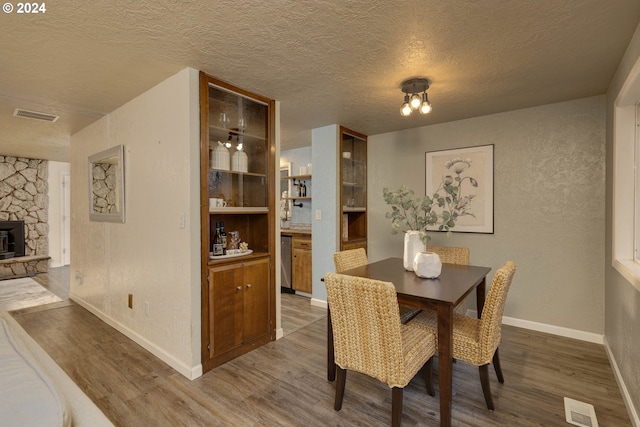 dining room featuring hardwood / wood-style flooring, built in features, a wood stove, and a textured ceiling