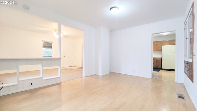 empty room with built in desk, light hardwood / wood-style floors, and ceiling fan