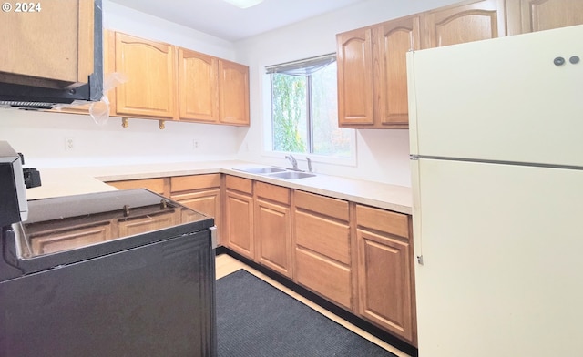 kitchen with stove, sink, light brown cabinetry, and white refrigerator