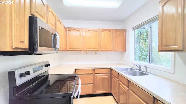 kitchen with stainless steel appliances, a sink, light brown cabinets, and light countertops