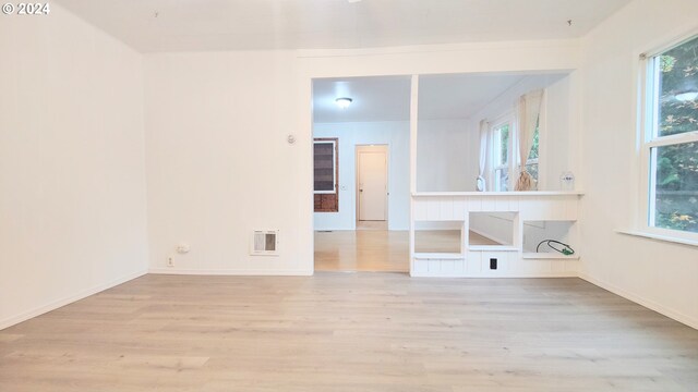 spare room with wood finished floors, plenty of natural light, and baseboards