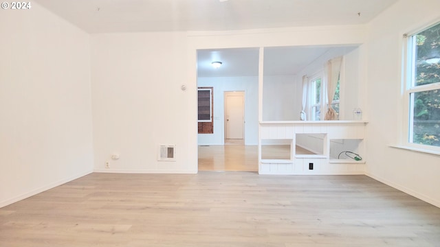 spare room featuring healthy amount of natural light, wood finished floors, and baseboards
