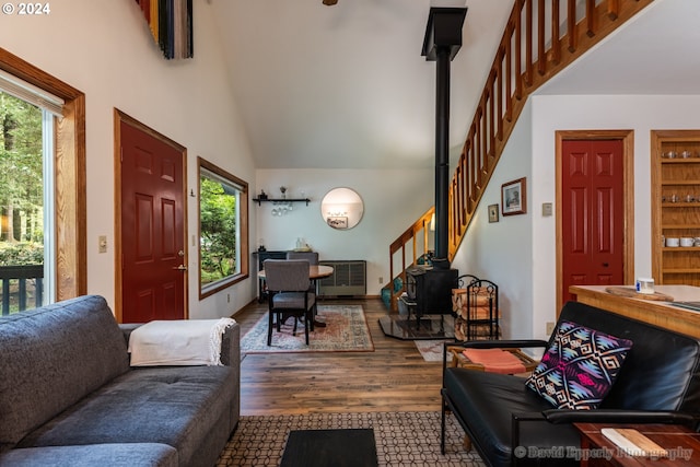 living room featuring hardwood / wood-style flooring, high vaulted ceiling, and a wood stove