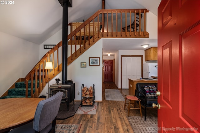 interior space with hardwood / wood-style flooring, high vaulted ceiling, and a wood stove