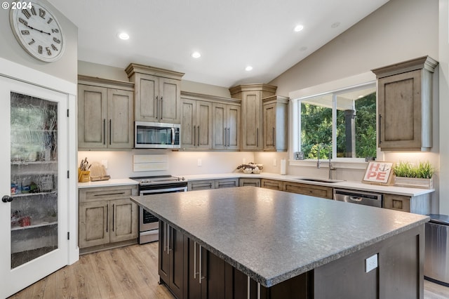 kitchen featuring vaulted ceiling, stainless steel appliances, sink, and a kitchen island