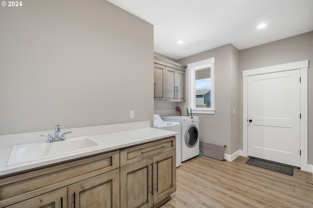 laundry room with cabinets, sink, washer and clothes dryer, and light wood-type flooring