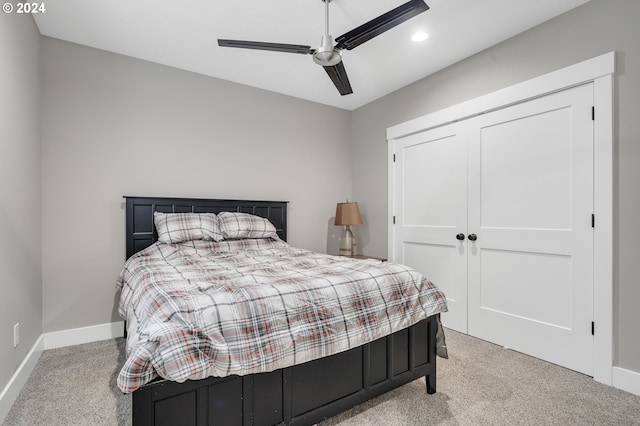 bedroom featuring light carpet, ceiling fan, and a closet