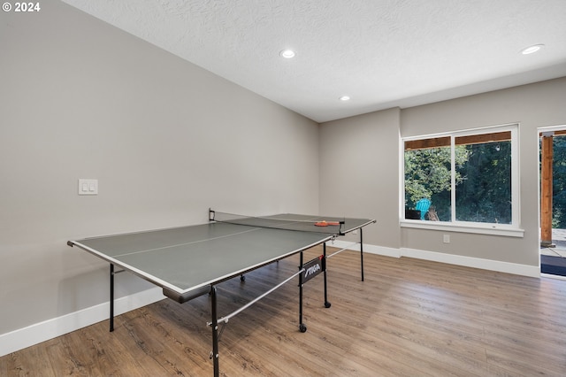 recreation room featuring light hardwood / wood-style floors and a textured ceiling