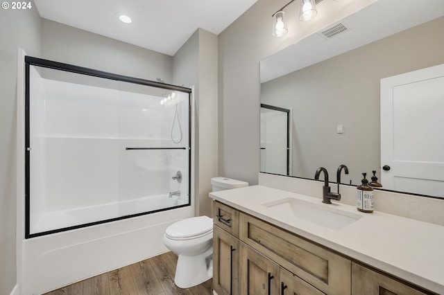 full bathroom with vanity, hardwood / wood-style flooring, enclosed tub / shower combo, and toilet