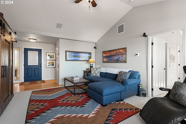 living area featuring high vaulted ceiling, a barn door, visible vents, and a ceiling fan