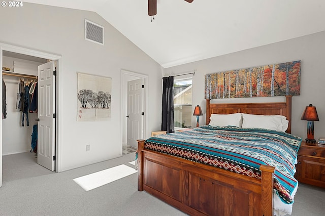 bedroom featuring a walk in closet, light colored carpet, visible vents, a ceiling fan, and vaulted ceiling