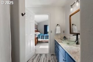 full bathroom featuring vaulted ceiling, wood finished floors, and vanity