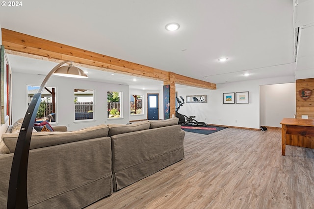 living room featuring plenty of natural light, light wood-type flooring, and beam ceiling