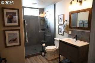 full bath with decorative backsplash, toilet, a stall shower, vanity, and wood finished floors