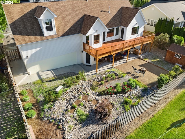 back of property with roof with shingles, a patio area, a fenced backyard, a fire pit, and a wooden deck