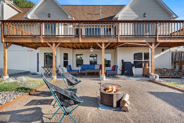 back of property with a patio area, an outdoor living space with a fire pit, a wooden deck, and roof with shingles