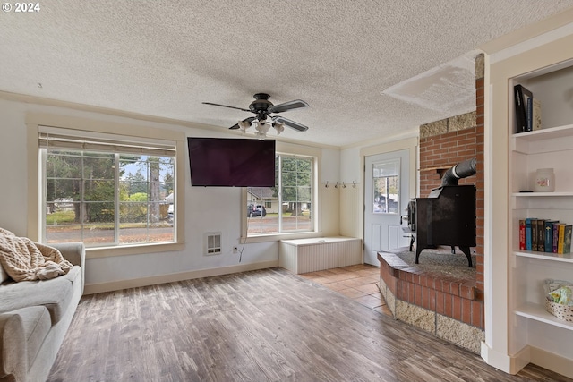 living room featuring a wood stove, ceiling fan, radiator heating unit, light hardwood / wood-style floors, and a textured ceiling