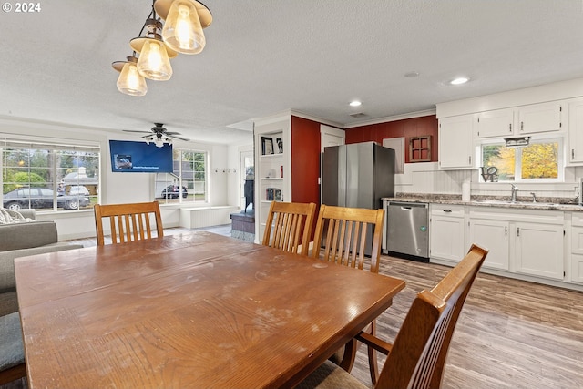 dining area with a textured ceiling, light hardwood / wood-style floors, ceiling fan, and sink