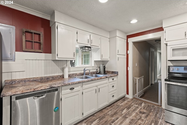 kitchen featuring white cabinets, dark wood-type flooring, appliances with stainless steel finishes, and a textured ceiling