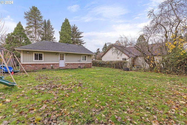 rear view of property with a playground and a lawn