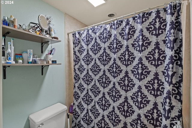 bathroom featuring toilet and walk in shower