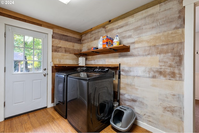 laundry area with separate washer and dryer, light hardwood / wood-style floors, and wood walls