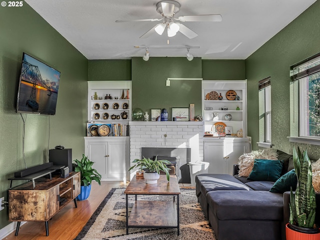 740 Florence Ave, Astoria, OR 97103 - living area with a ceiling fan, wood finished floors, rail lighting, built in features, and a brick fireplace
