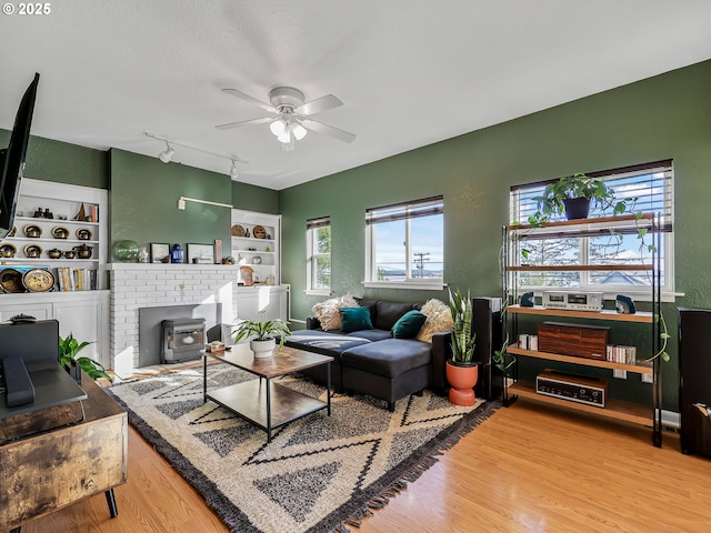 740 Florence Ave, Astoria, OR 97103 - living room with ceiling fan, wood finished floors, built in shelves, rail lighting, and a wood stove