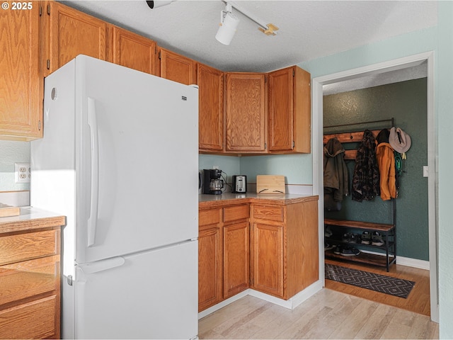 740 Florence Ave, Astoria, OR 97103 - kitchen featuring freestanding refrigerator, light wood finished floors, light countertops, brown cabinets, and rail lighting
