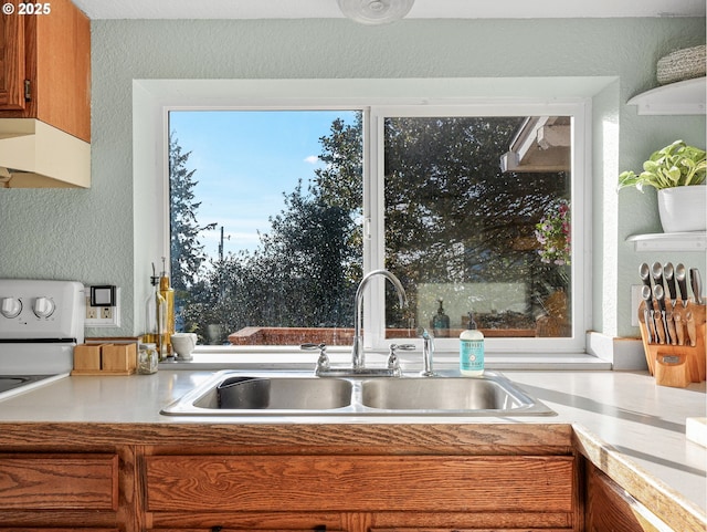 740 Florence Ave, Astoria, OR 97103 - kitchen featuring a sink, under cabinet range hood, brown cabinets, a textured wall, and light countertops