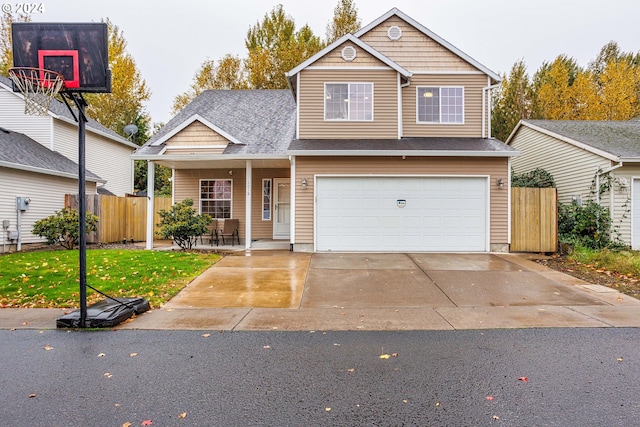 1018 NE Mariners Loop, Portland, OR 97211 - view of front facade with fence, a garage, driveway, and covered porch