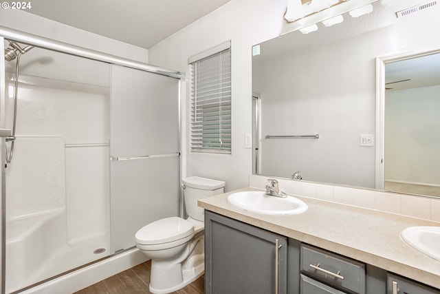 bathroom featuring toilet, vanity, wood-type flooring, and walk in shower