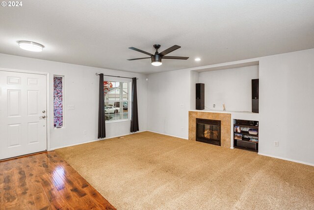 unfurnished living room with a fireplace, wood-type flooring, a textured ceiling, and ceiling fan