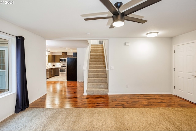 1018 NE Mariners Loop, Portland, OR 97211 - empty room featuring light colored carpet, ceiling fan, stairway, and baseboards