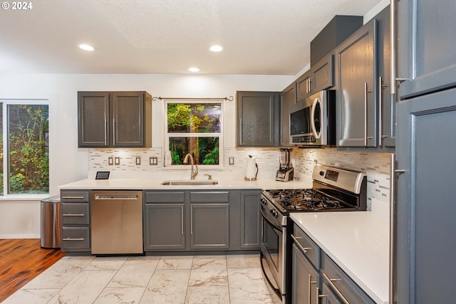 kitchen with a textured ceiling, tasteful backsplash, sink, and stainless steel appliances