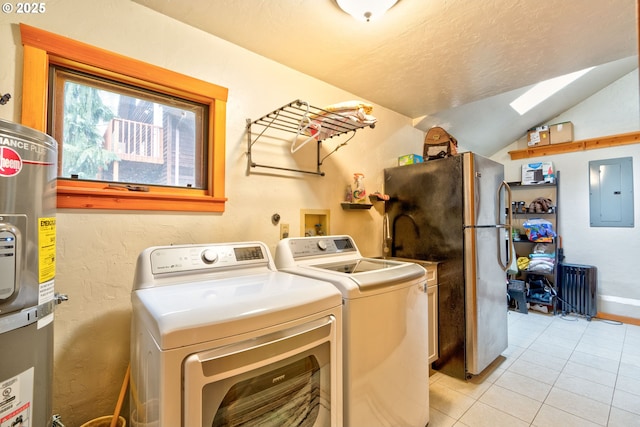 laundry room featuring water heater, a skylight, washing machine and clothes dryer, light tile patterned flooring, and electric panel