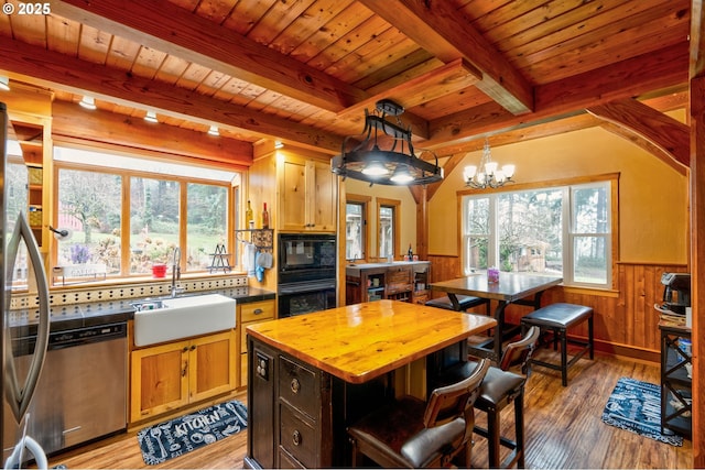 kitchen with hardwood / wood-style floors, a center island, black appliances, decorative light fixtures, and sink