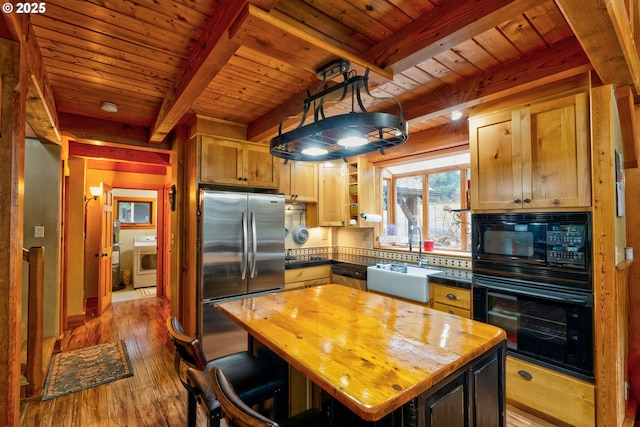 kitchen featuring washer / dryer, sink, beam ceiling, a kitchen island, and black appliances