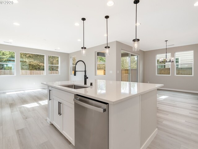 kitchen featuring stainless steel electric stove, wall chimney range hood, pendant lighting, and a center island with sink